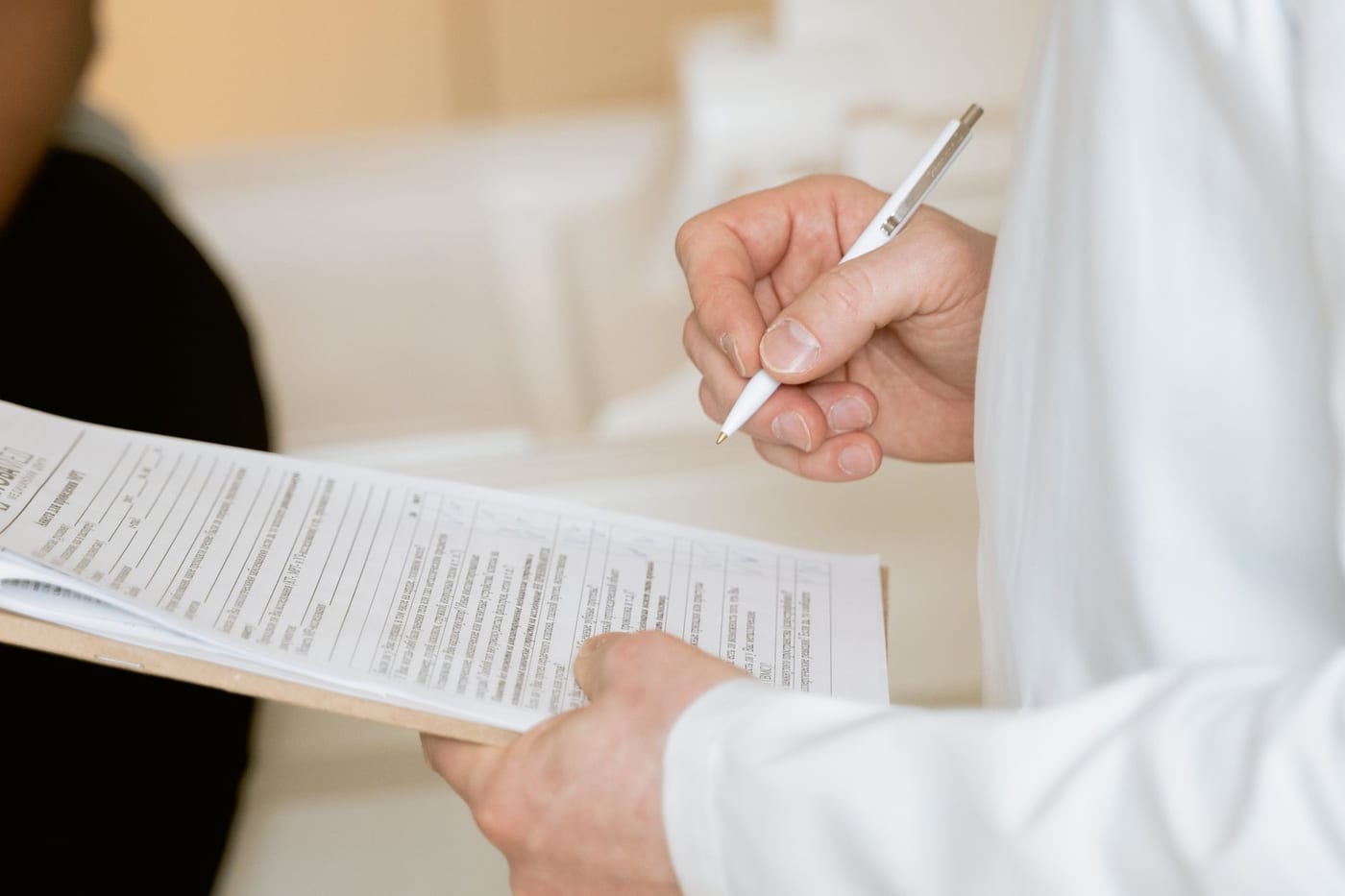 A close-up of hands holding a printed clinical document, a pen poised over the text.